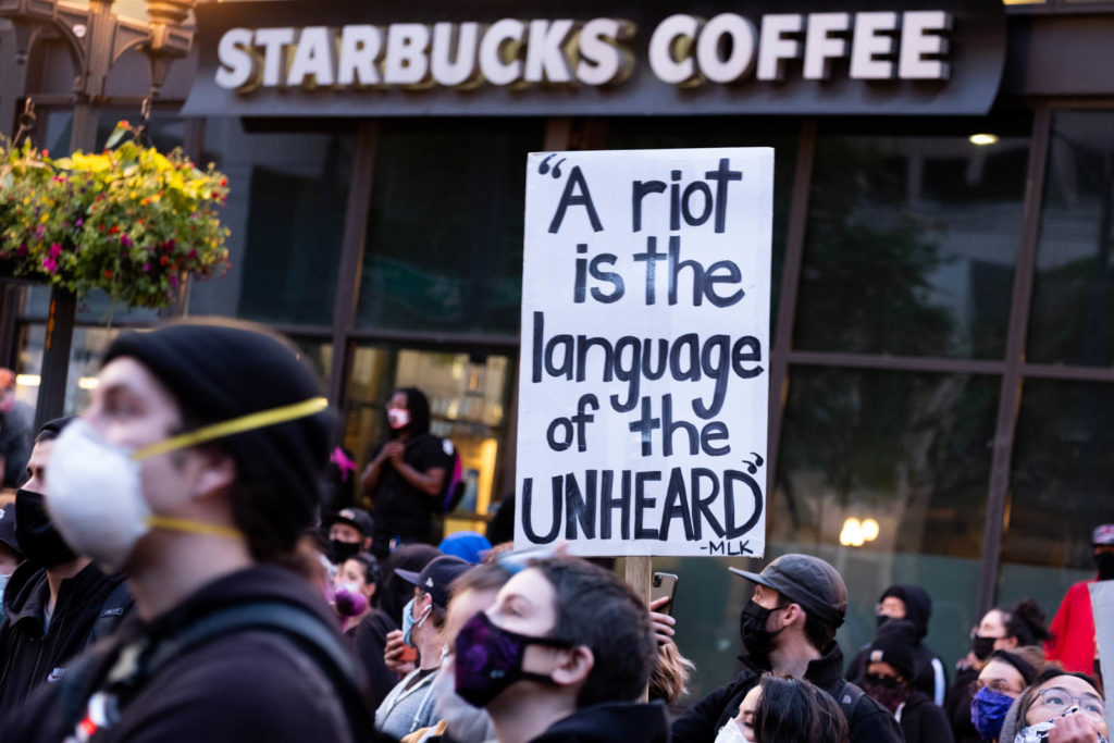 A sign reads, "A riot is the language of the unheard"