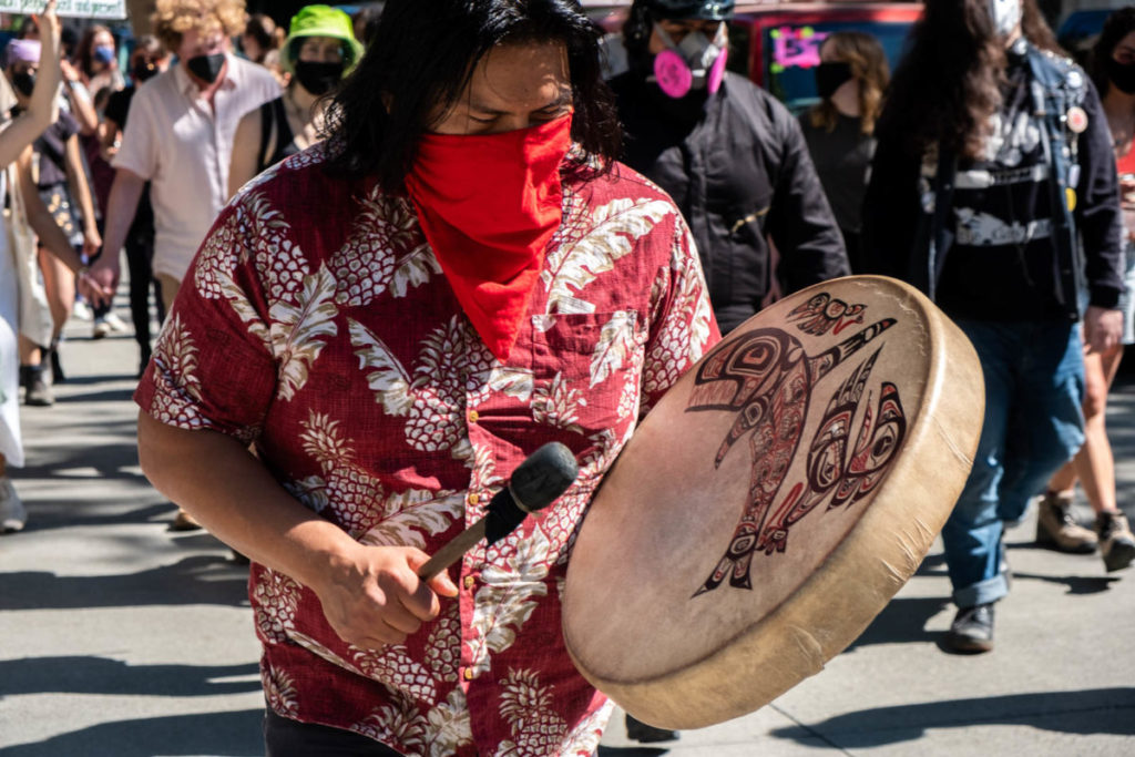 A protestor beats a native drum toward the front of the march