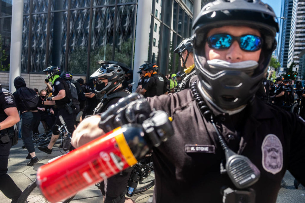 An SPD officer threatens protesters with pepper spray moments after dozens of policemen rode their bikes into the march, tackling and arresting several people