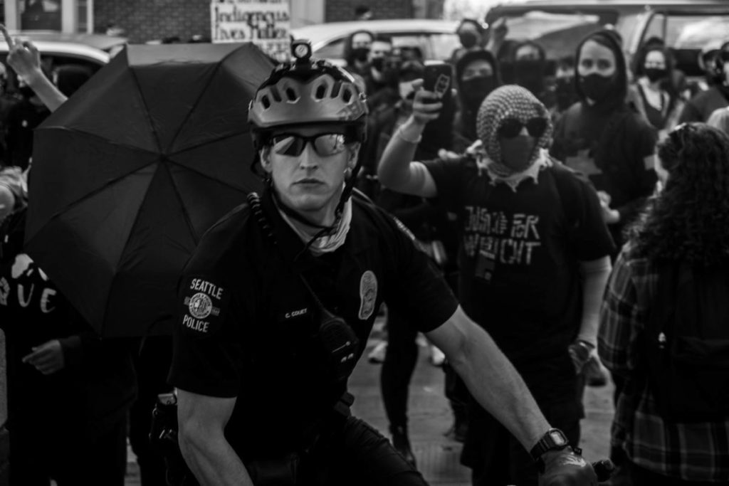 A police officer looks directly into the camera as he and fellow officers try to direct and restrain the crowd of marchers