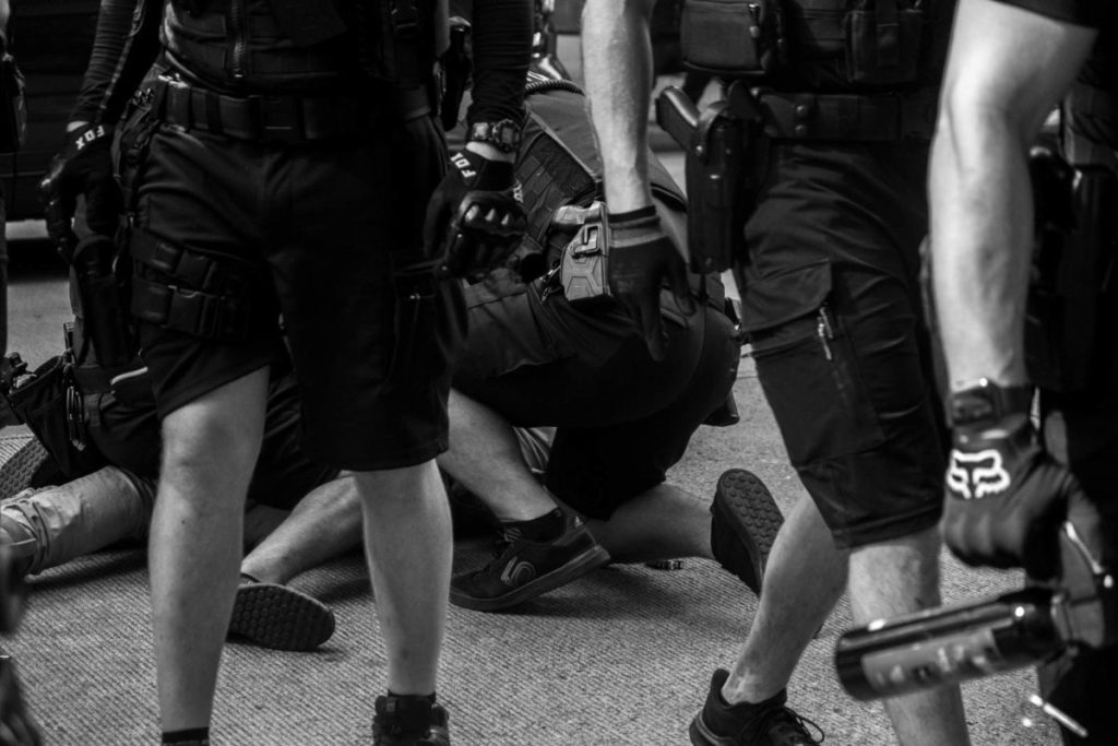 Police officers tackle and immobilize a protester on 4th Avenue