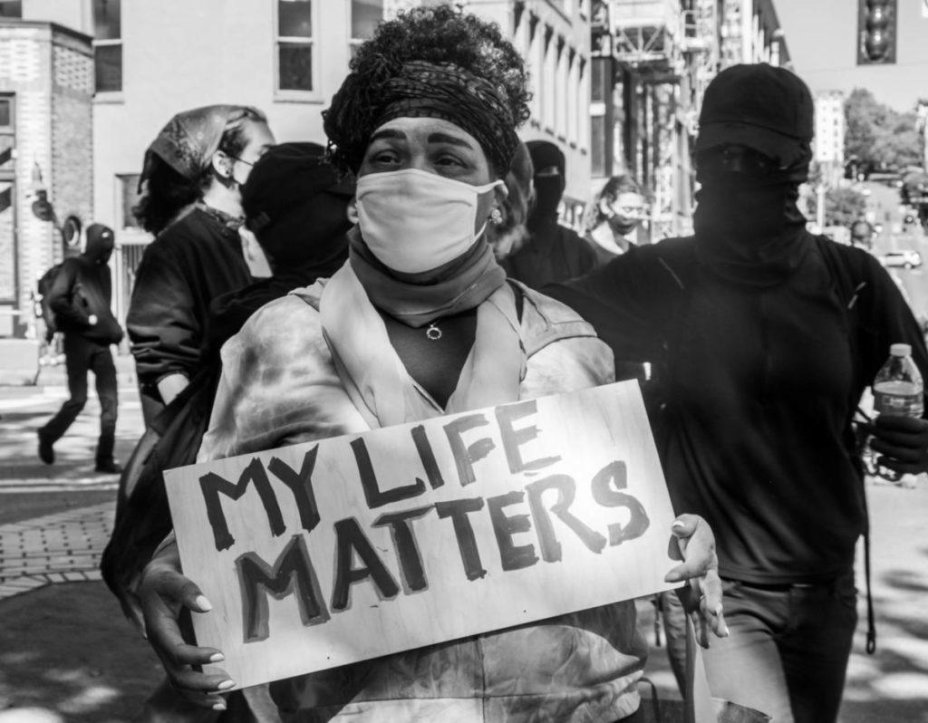 A woman stands holding a “My Life Matters” sign on the street corner of 2nd Avenue and Washington Street, moments after the march came to a close