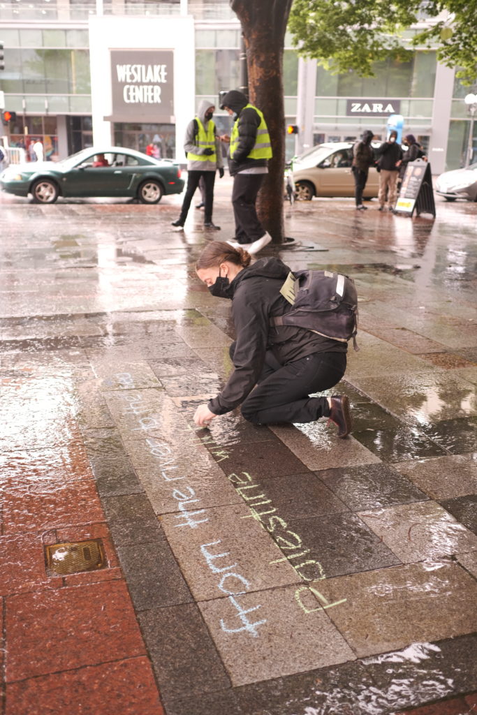 A woman writes one of the chants in chalk, “From the river to the sea, Palestine will be free.”