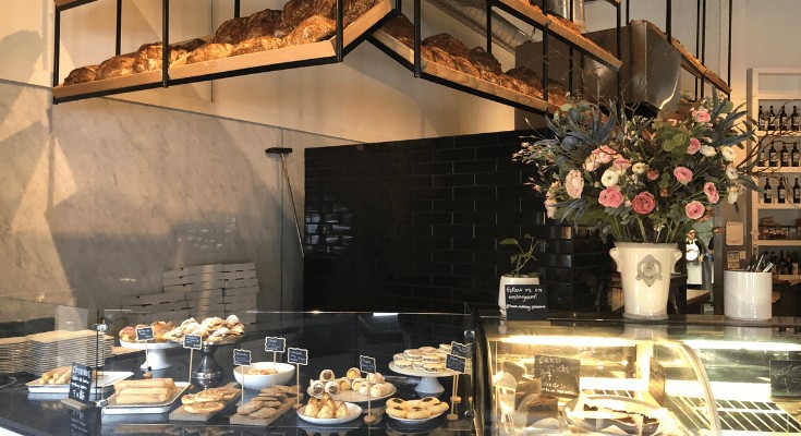 Display case featuring flowers, breads, and desserts.