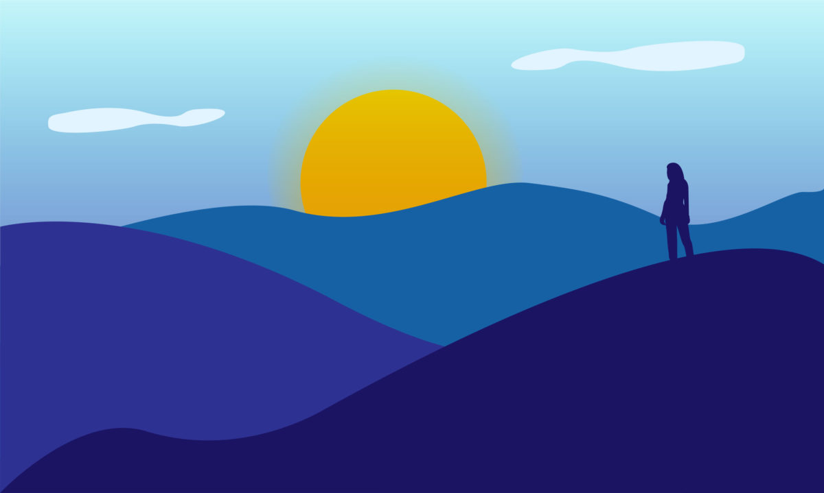 Woman standing on a mountain looking at the sunrise